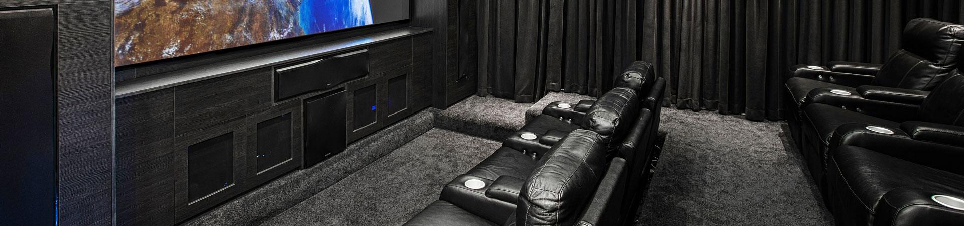 Flexi Renovations Perth Luxury home theatre with black leather recliner seating, custom dark cabinetry, large screen TV and blackout curtains