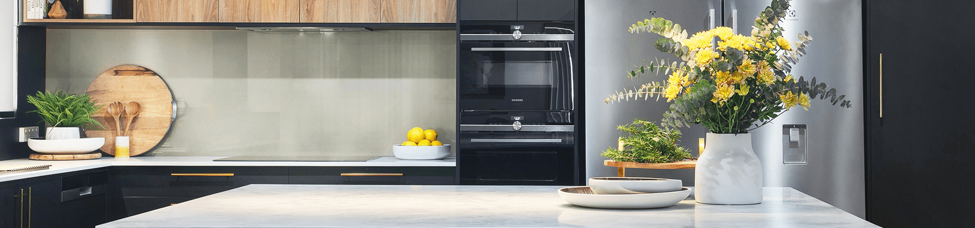 Flexi Renovations Perth Modern Perth kitchen renovation featuring black gloss cabinetry, timber accents, built-in Siemens ovens and stone benchtops