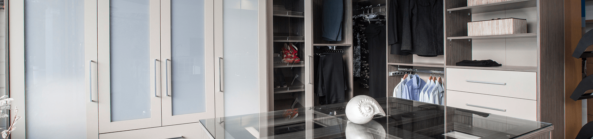 Flexi Renovations Perth Modern walk-in wardrobe with frosted glass doors, hanging clothes, shelving, and drawers in grey wood-grain finish
