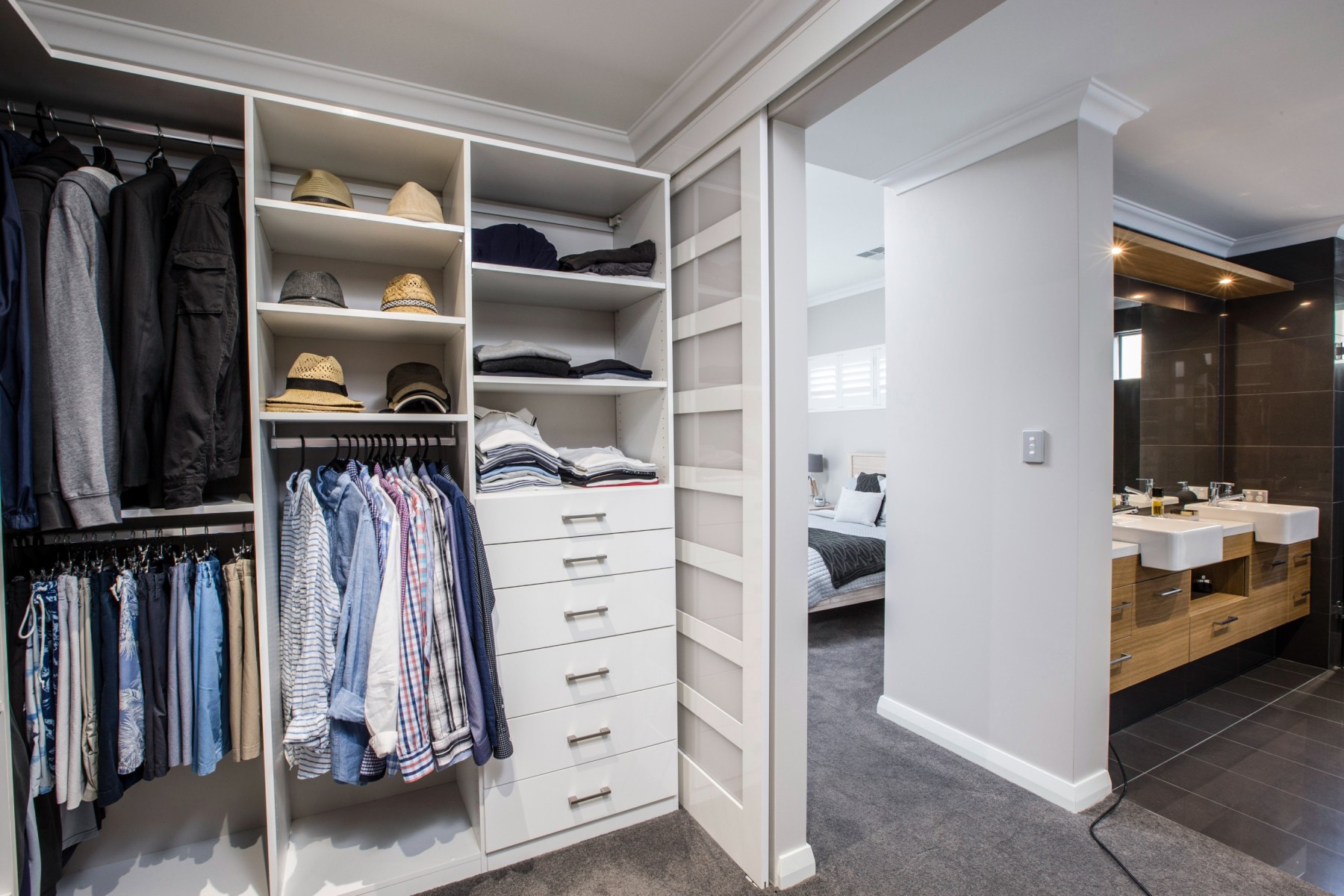 Custom dressing room in Dalkeith, Perth, WA featuring white shelving, drawers, hanging clothes, and hat storage for a renovated bedroom wardrobe.
