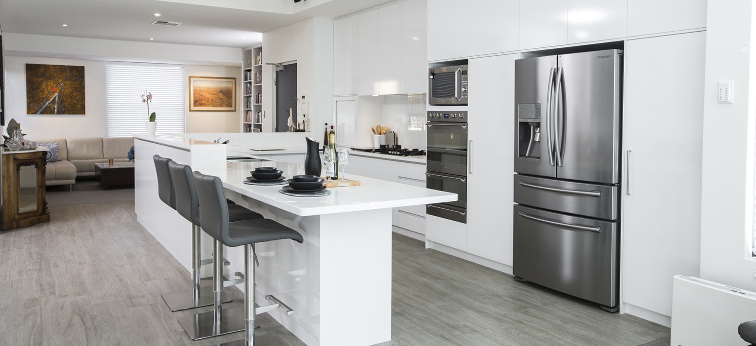 Modern kitchen design in Subiaco, Perth. Features a white island, stainless steel fridge, and grey bar stools. Renovated space in Western Australia.