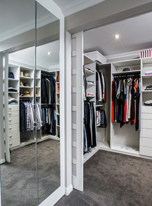 Built-in closet with mirror, shelves, drawers, and organized clothing. Modern closet design, A29V6987.