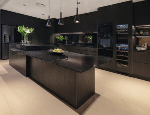Sleek Industrial Luxe kitchen in Balcatta featuring dark wood cabinetry, stone island, and modern pendant lighting.