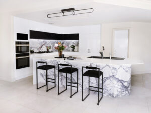 Bold minimalist kitchen in Applecross featuring a marble island, black stools, and modern appliances. 890-11.