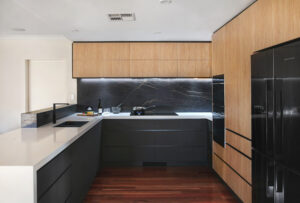 Clean Contemporary Kitchen in Bateman featuring dark cabinets, marble backsplash, and modern design elements.