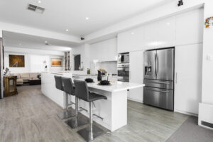 Contemporary minimalist kitchen in Subiaco: island with stools, sleek white cabinetry, and stainless steel appliances.