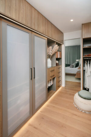 Soft minimalist walk-in robe in Floreat, featuring frosted glass doors and warm wood tones.